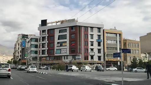 تصویری شهری از یک خیابان پرتردد با ساختمان‌های تجاری و اداری، نشان‌دهنده موقعیت کافه قانون در محیطی پویا برای مشتریان.