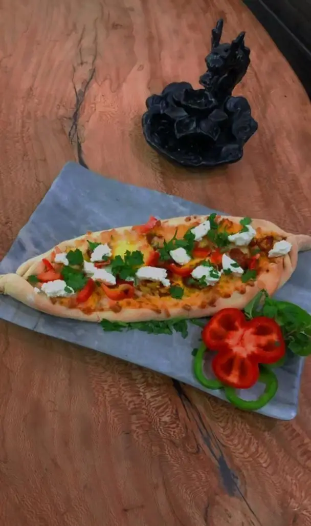 پیده لذیذ کافه ایندرا: نان قایقی شکل با پنیر سفید، فلفل دلمه‌ای، سبزیجات تازه و تخم‌مرغ، روی سینی مرمری. غذای ایده‌آل.