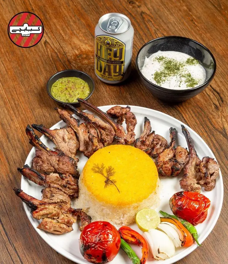 شیشلیک و کباب بره لذیذ کبابچی اکسپرس اکباتان با پلو زعفرانی، گوجه کبابی، سس سبز، ماست و نوشیدنی مالت. بهترین کباب ایرانی.