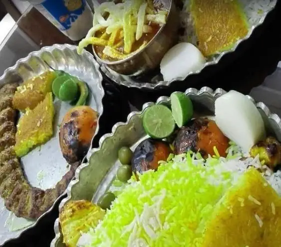 میز جذاب غذای رستوران برکتی: چلوکباب، برنج زعفرانی، خورشت، گوجه کبابی، لیمو و سبزیجات تازه. تجربه طعم اصیل ایرانی.