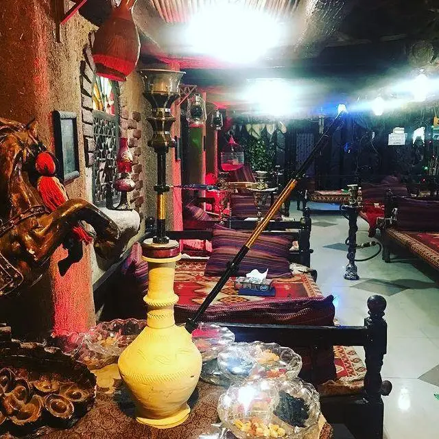 تصویری از فضای گرم و سنتی سفره خانه شبستان با دکوراسیون اصیل، تخت‌های راحت، و انواع قلیان در محیطی آرامش‌بخش و دلنشین.