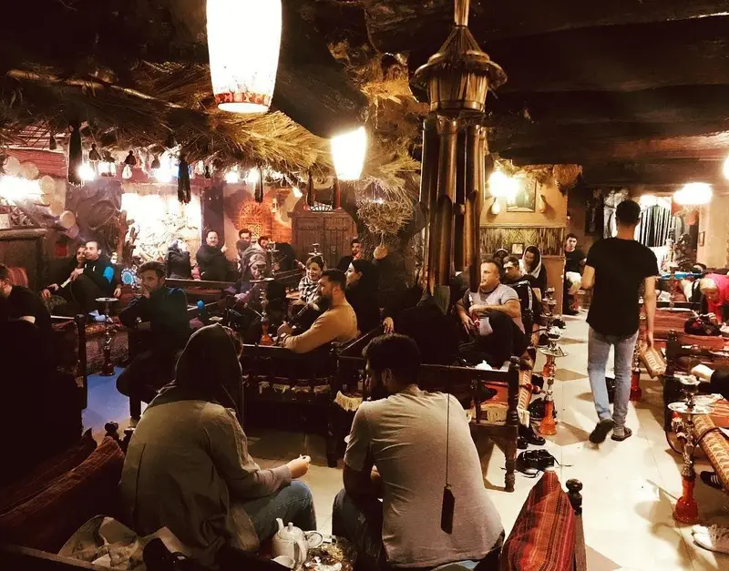 نمایی از فضای سنتی و دنج سفره خانه شبستان با مشتریان مشغول گفتگو و قلیان کشیدن، محیطی دلنشین برای دورهمی.