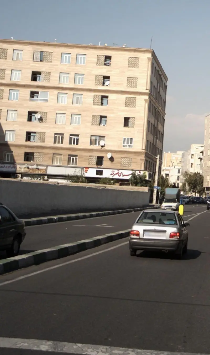 تصویر نمای بیرونی ساختمان شیرینی سرای قصرقند در خیابانی پرتردد در تهران، با معماری زیبا، پنجره‌ها و خودروهای در حال حرکت.