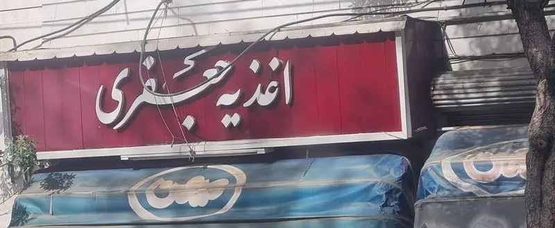 تصویری از تابلوی جذاب و برجسته اغذیه جعفری، یک فست فود محبوب با غذاهای لذیذ. نمای بیرونی مغازه جعفری.