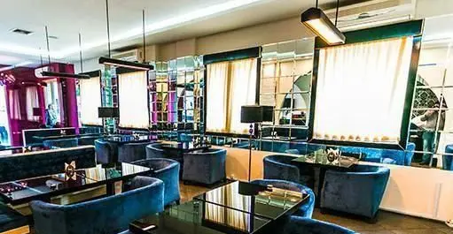 فضای داخلی دنج و شیک کافه رستوران کازابلانکا با مبلمان مخمل آبی، میزهای براق و دیوارپوش آینه‌ای، مناسب برای اوقات فراغت.