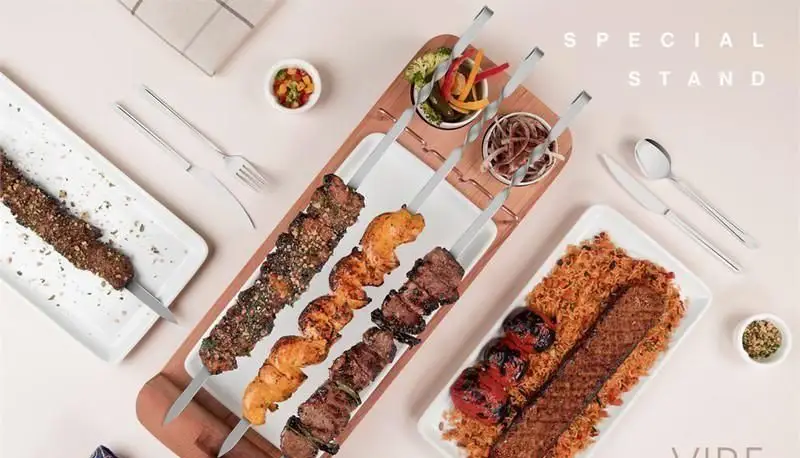 انواع کباب های رستوران وایب: کوبیده، جوجه کباب و شیشلیک با برنج زعفرانی، گوجه کبابی و مخلفات در میز چوبی شیک و مدرن.