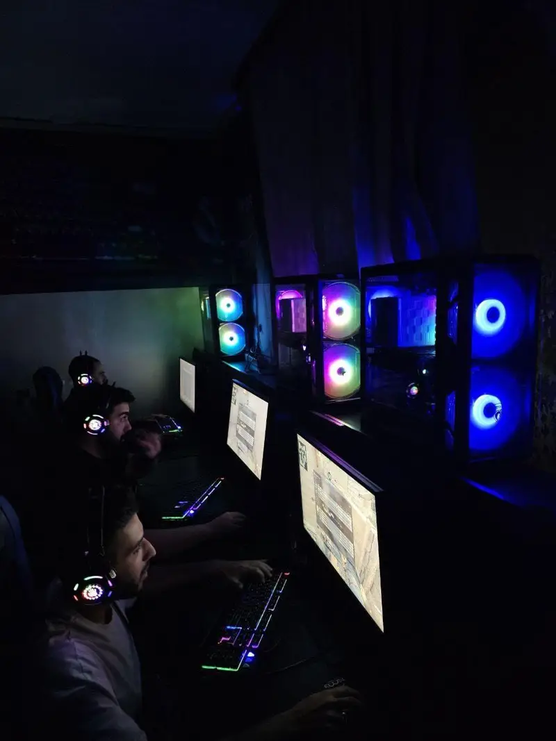 گیم نت جونیور: بازیکنان در حال تجربه بازی‌های ویدئویی در محیطی با کامپیوترهای مجهز به نورپردازی RGB چشم‌نواز و کیبوردهای رنگی.