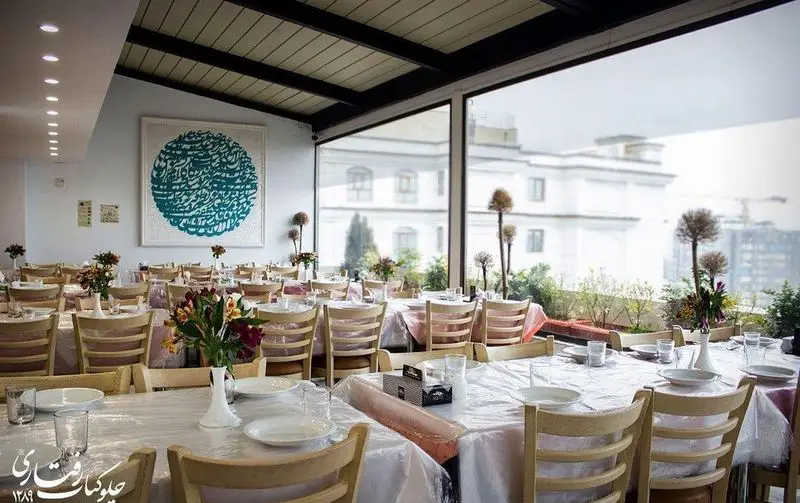 تصویری از فضای دلنشین رستوران چلوکباب رفتاری با چیدمان میز و صندلی، دکوراسیون زیبا و منظره چشم‌نواز شهری از پنجره‌های بزرگ.