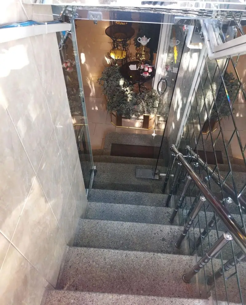 تصویری از پله‌های ورودی کافی شاپ فرد یاس، منعکس کننده فضای دنج و دلنشین آن با دکوراسیون سنتی، سماور و گیاهان.