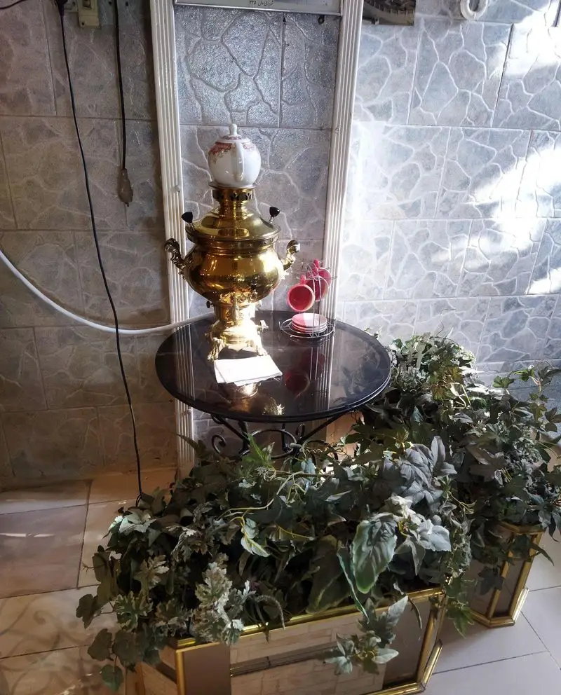 سماور برنجی و سرویس چای در کافی شاپ فرد یاس، محیطی گرم و سنتی با دکوراسیون دلنشین و گیاهان سبز.