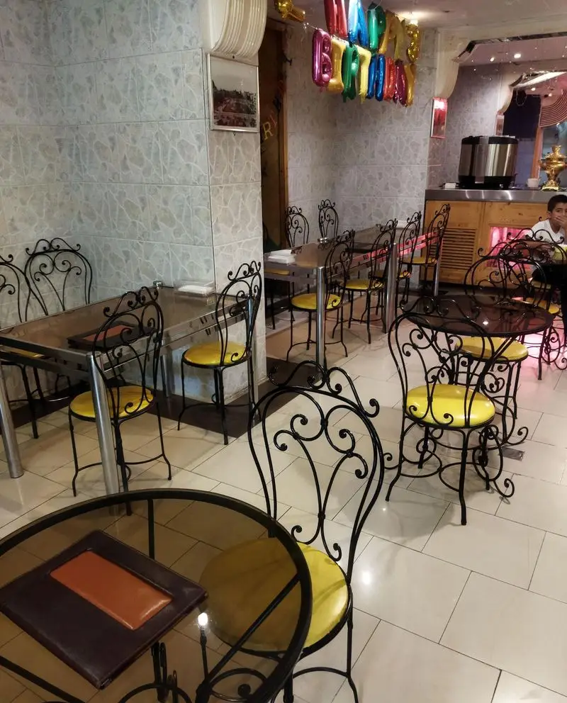 دکوراسیون داخلی کافی شاپ فرد یاس با میز و صندلی‌های فرفورژه و نشیمن‌های زرد، فضایی دلنشین برای جشن تولد و پذیرایی از مشتریان.