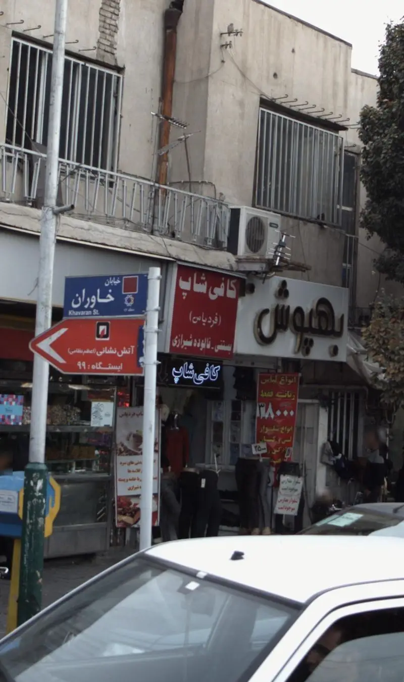 نمای یک کافی شاپ به نام فرد یاس در خیابان خاوران تهران، با تابلوی بزرگ فروش بستنی و فالوده شیرازی، در یک روز ابری.