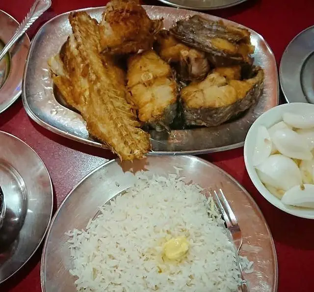 غذای اصیل رستوران لاکان: سینی ماهی سرخ شده تازه، برنج ایرانی کته با کره و پیاز ترشی، لذت طعم واقعی در رشت.