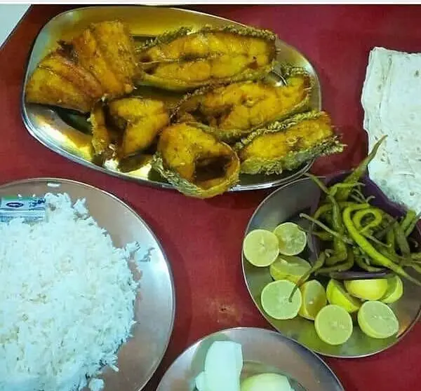 یک میز پر از غذای رستوران لاکان: ماهی سرخ شده طلایی با برنج سفید، فلفل سبز تند و برش‌های لیمو. وعده‌ای دلچسب و کامل.