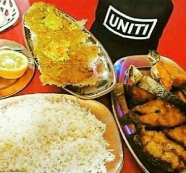 غذای خوشمزه و مجلل در رستوران لاکان شامل برنج سفید، ماهی سرخ شده و ته چین زعفرانی. تجربه‌ای بی‌نظیر از طعم اصیل ایرانی.