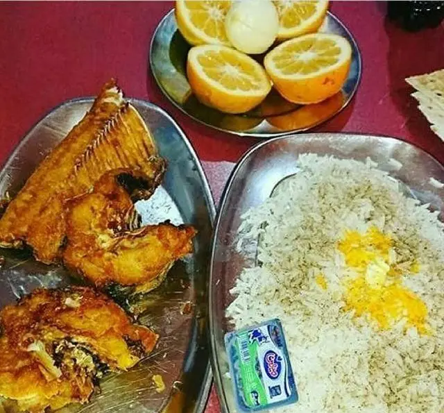 غذای خوشمزه رستوران لاکان: ماهی سرخ شده لذیذ و چلو زعفرانی با کره تازه، همراه با پرتقال تازه و آبدار. تجربه‌ای اصیل از غذاهای ایرانی.