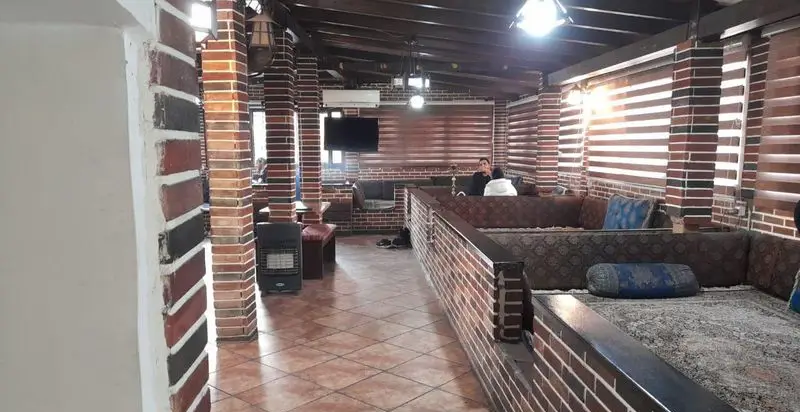 فضای داخلی کافه رستوران کندو با دکوراسیون سنتی و دیوارهای آجری، سقف چوبی، مبلمان راحت و فضای دلنشین برای مشتریان.