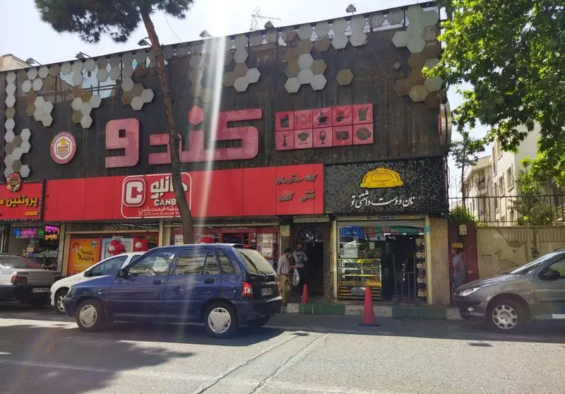 نمای جذاب کافه رستوران کندو در تهران، ساختمان چندمنظوره با فروشگاه Canb و نانوایی "نان دوست داشتی تو" در یک روز روشن.