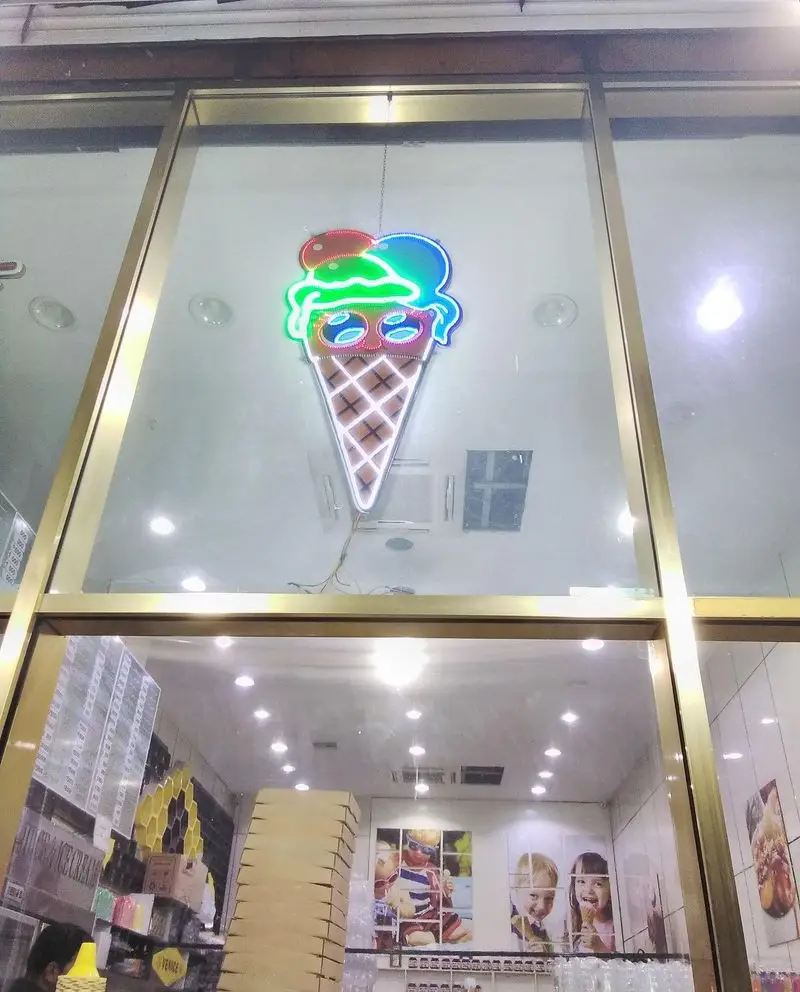 تصویری از ویترین جذاب بستنی ونیز، با تابلو نئونی روشن بستنی سه اسکوپ رنگی و دکوراسیون داخلی با عکس‌های کودکان در حال لذت بردن از بستنی