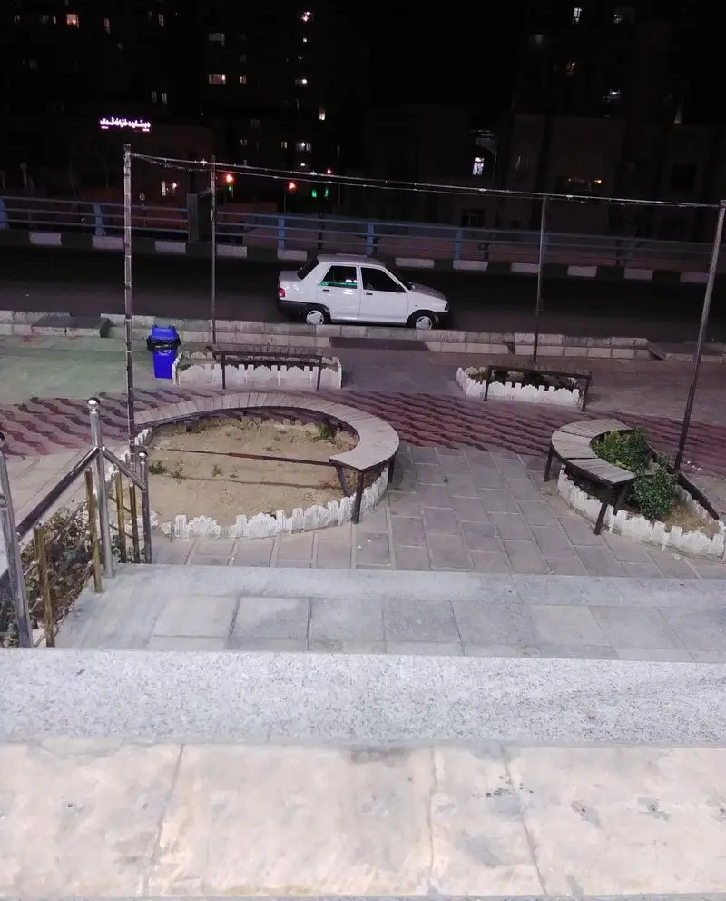 نمای بیرونی بستنی ونیز در شب، با ماشینی سفید پارک شده در خیابان، پله‌های ورودی و فضای پیاده‌رو با نیمکت‌ها.