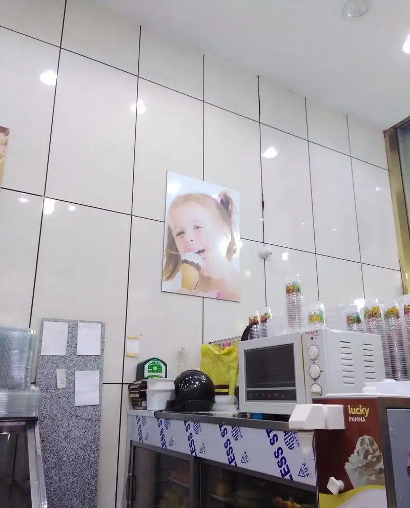 محیط داخلی دلنشین بستنی ونیز با پیشخوان مرتب، دستگاه‌های آماده‌سازی و پوستر کودک بستنی‌خور. تجربه دسر تازه و نوشیدنی.