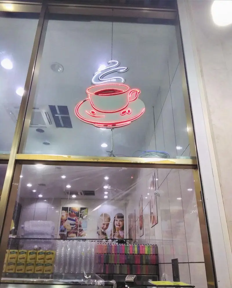 نمای بیرونی بستنی فروشی و کافه بستنی ونیز، با تابلو نئون فنجان قهوه قرمز و سفید، نشان دهنده فضای دلنشین و محصولات لذیذ