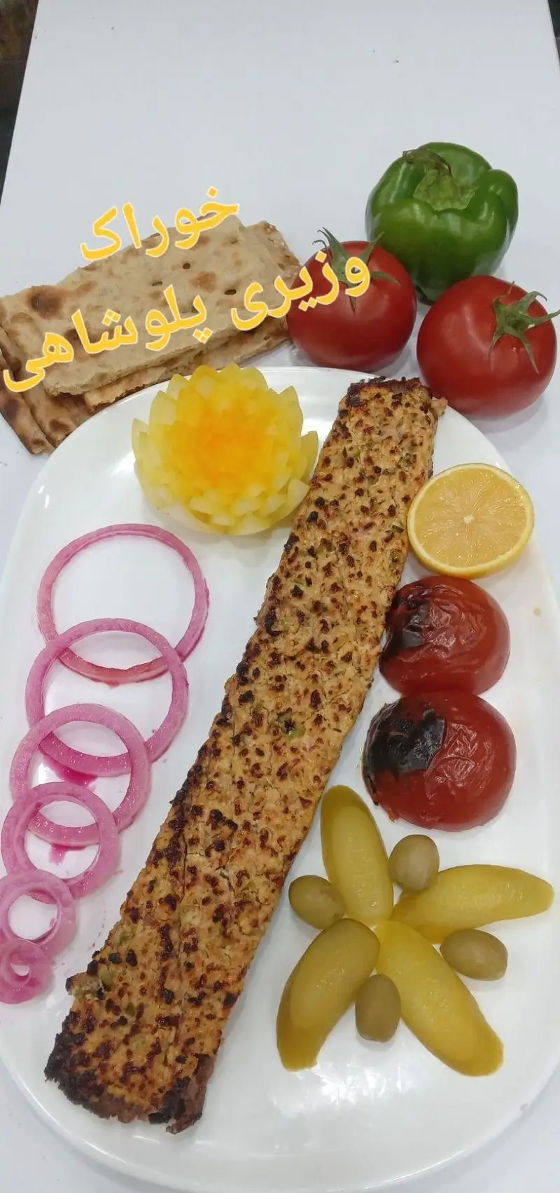 خوراک کباب وزیری لذیذ رستوران پلوشاهی با گوجه کبابی، نان تازه، پیاز، لیمو و ترشیجات، تجربه‌ای شاهانه از طعم اصیل ایرانی.