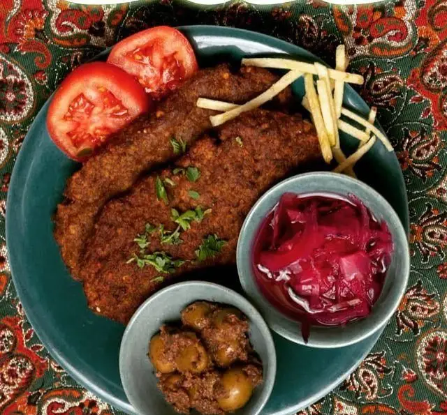 یک بشقاب غذای لذیذ ایرانی از رستوران فلوت شامل دو تکه کوکو یا کتلت آبدار، گوجه، سیب زمینی سرخ کرده، زیتون پرورده و ترشی لبو تازه.