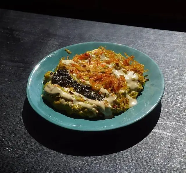 بشقاب خوش‌رنگ و لذیذ رستوران فلوت: شامل پوره یا کتلت سبز، تاپینگ پیاز داغ ترد، خاویار سیاه و سس خامه‌ای، با چیدمانی هنرمندانه.