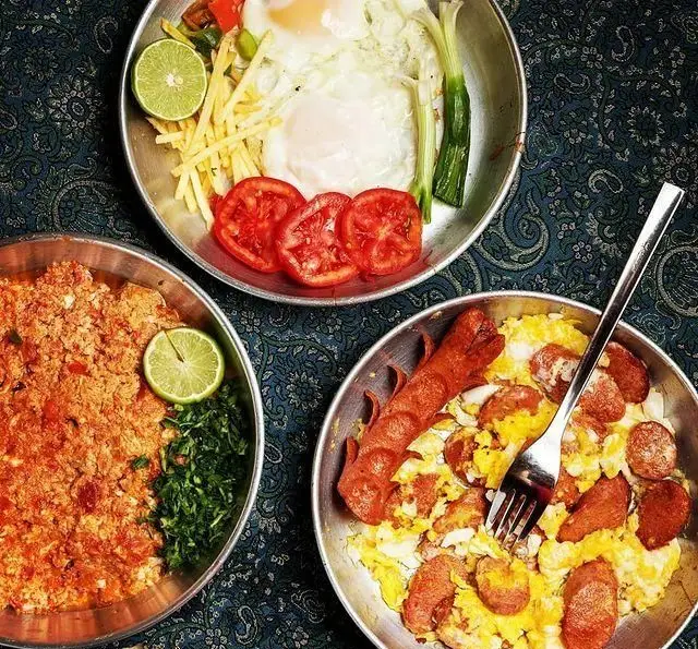 انواع صبحانه لذیذ رستوران فلوت: نیمرو با گوجه و سیب‌زمینی سرخ‌کرده، املت گوجه و سبزی تازه، و سوسیس تخم‌مرغ. تجربه‌ای خاص.