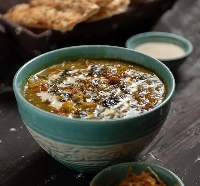 یک کاسه آش سنتی ایرانی با کشک، پیاز و نعناع داغ، همراه نان تازه در رستوران فلوت. غذای اصیل و خوشمزه برای ناهار.