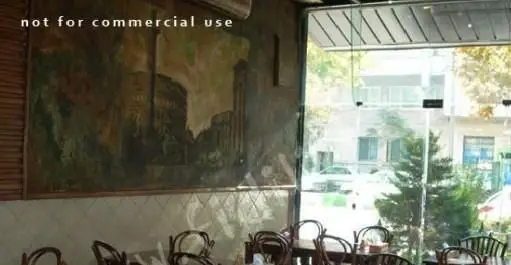 نمایی از فضای داخلی رستوران ایتالیایی ناپولی با دکوراسیون جذاب، نقاشی دیواری بزرگ و میز و صندلی چوبی کنار پنجره با دید خیابان.