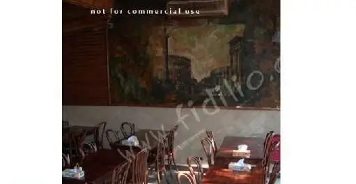 فضای داخلی رستوران ایتالیایی ناپولی با چیدمان میز و صندلی چوبی، دکوراسیون سنتی و نقاشی دیواری زیبا از مناظر روم باستان.