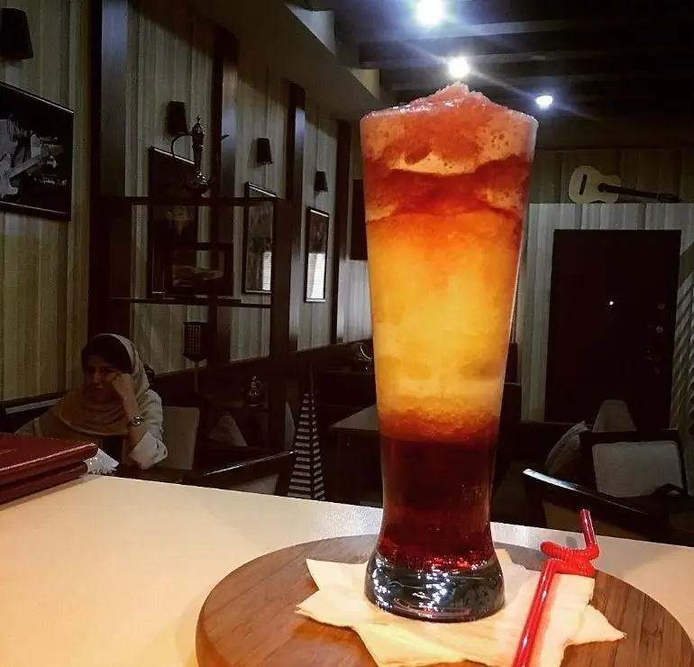 نوشیدنی اسموتی چندلایه و خنک کافه نتو با ترکیبی دلپذیر از رنگ‌ها در محیط دنج و شیک کافه. لذت یک نوشیدنی عالی.