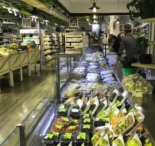 نمای داخلی روشن و دلباز گورمه مارکت مزرعه ماهشام با ویترین‌های مدرن پر از میوه‌های تازه، سبزیجات و محصولات غذایی با کیفیت.
