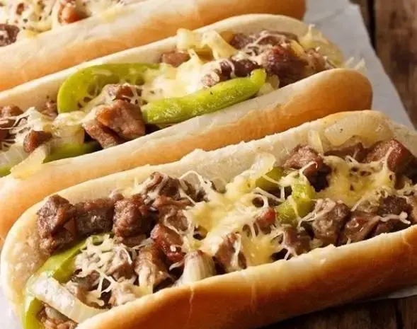 تصویری از ساندویچ‌های استیک و پنیر لذیذ آماده سرو، شامل گوشت تازه، پنیر آب شده و فلفل در نان تازه، محصولات گورمه مارکت مزرعه ماهشام.