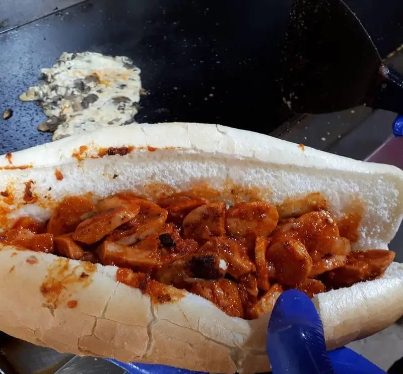 ساندویچ سوسیس تند و خوشمزه در نان باگت از فلافل دو لپی، با تخم مرغ و قارچ در حال پخت. غذای گرم و لذیذ.