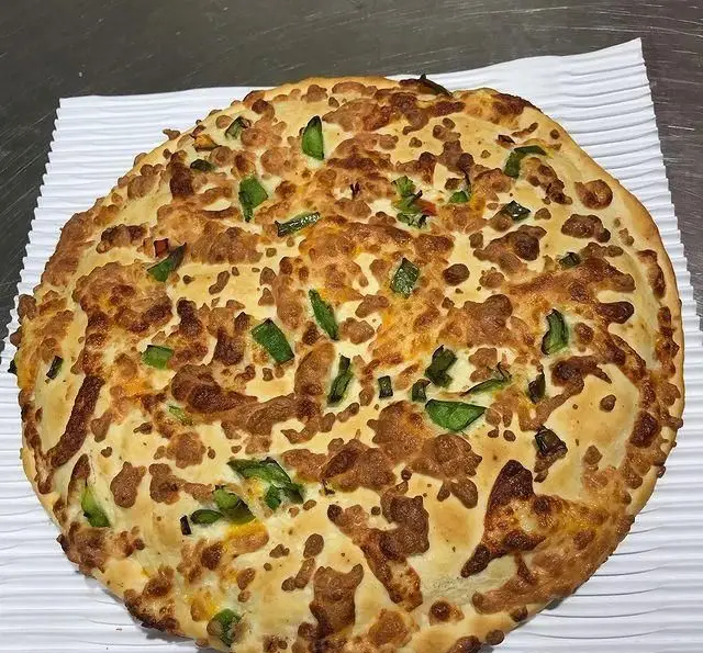 یک پیتزای داغ و لذیذ فست فود فایر با پنیر پیتزای طلایی برشته و تکه‌های فلفل دلمه‌ای سبز، تجربه‌ای عالی از طعم.