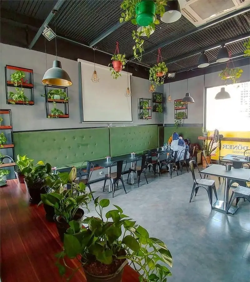 فضای داخلی دنج و مدرن فست فود دونر لکوم با دکوراسیون گیاهی، میز و صندلی راحت، محیطی دلنشین برای سرو دونر و فست فود.