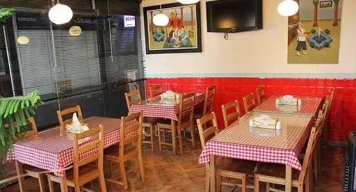 رستوران مستر دیزی: دکوراسیون داخلی با میز و صندلی چوبی، رومیزی شطرنجی، دیوار کاشی قرمز و فضایی گرم و صمیمی برای تجربه غذایی دلپذیر.