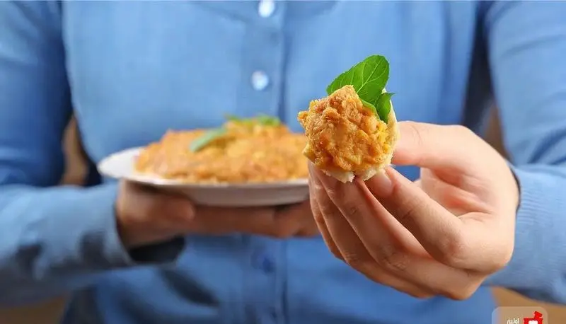 سرو دیزی سنتی ایرانی از رستوران مستر دیزی؛ مشتری در حال میل کردن یک لقمه خوشمزه با نان و سبزی تازه، تجربه‌ای دلنشین از غذای اصیل.