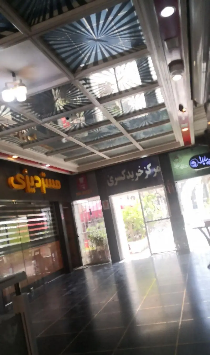 ورودی مدرن رستوران مستر دیزی در مرکز خرید کسری با سقف تزیینی، تابلوی نارنجی جذاب و فضای داخلی روشن و دلنشین.