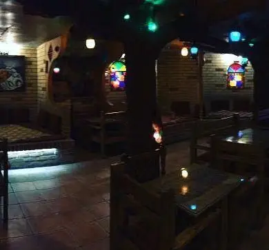 دکوراسیون داخلی جذاب و سنتی سفره خانه کاج با نورپردازی رنگی، درخت مرکزی، تخت‌های سنتی و محیطی گرم و دلنشین.