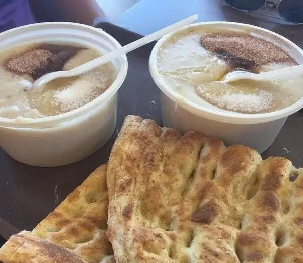 دو کاسه حلیم تازه و خوشمزه حلیم صبا، آماده سرو با دارچین، شکر و روغن، در کنار نان سنگک داغ برای صبحانه ای ایرانی.