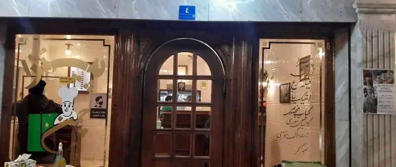 نمای بیرونی جذاب پیتزا چمن با درب ورودی چوبی شیک و پنجره‌های بزرگ، لوگوی سرآشپز، علائم ورودی و شماره پلاک ۳.