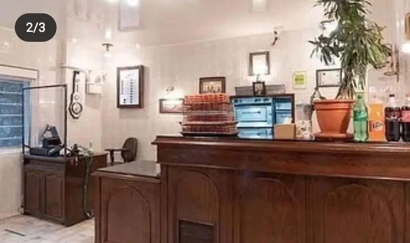 نمایی از دکوراسیون داخلی مدرن و پیشخوان پیتزا چمن، با نمایش پیتزاهای آماده و نوشیدنی‌ها برای سرویس‌دهی عالی و فست فود.