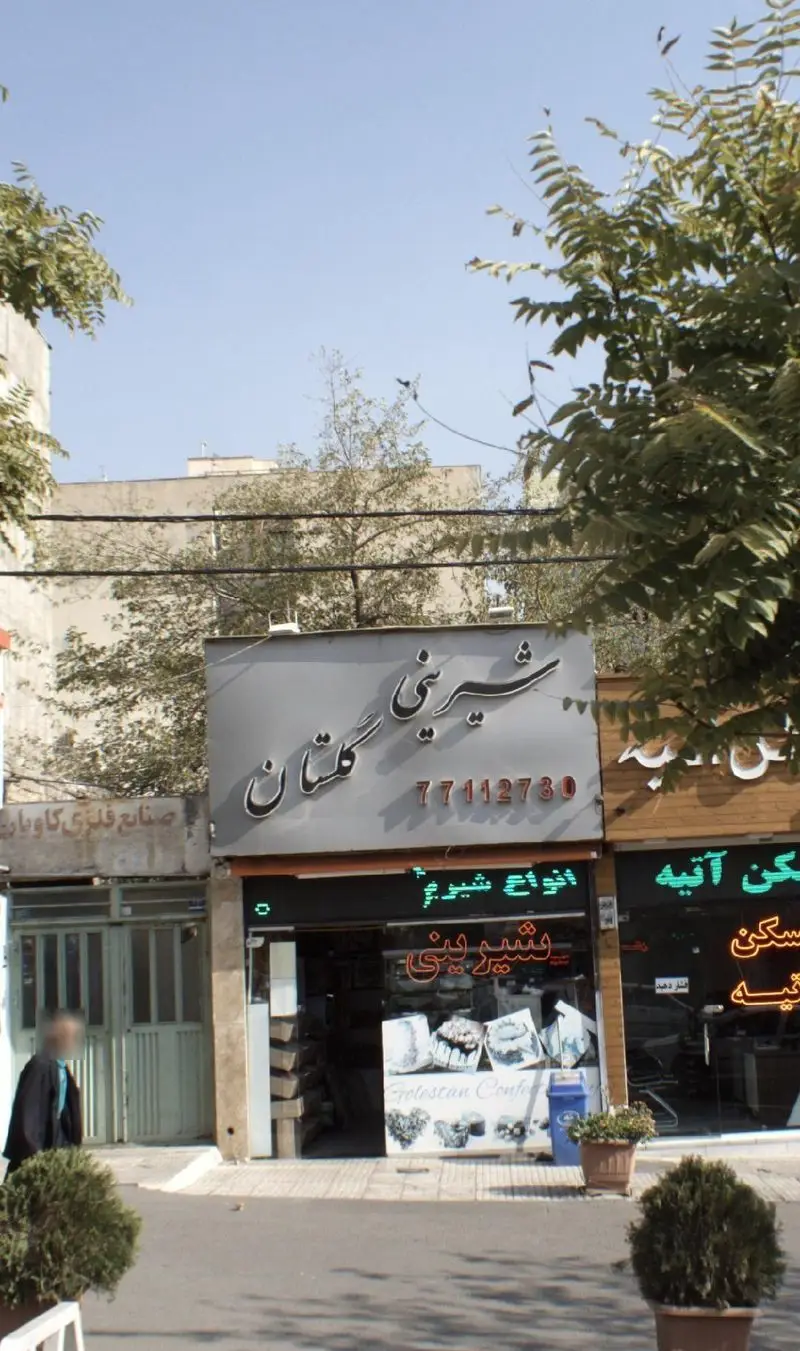 نمای بیرونی شیرینی فروشی گلستان با تابلوی شیرینی گلستان و شماره تماس ۷۷۱۱۲۷۳۰، انواع شیرینی و کیک را نمایش می دهد.