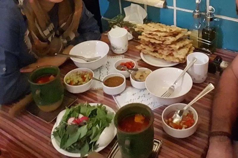 میز پر از غذای سنتی دیزی در رستوران دیزی، همراه با نان تازه، سبزی خوردن و مخلفات لذیذ. تجربه ای اصیل ایرانی.