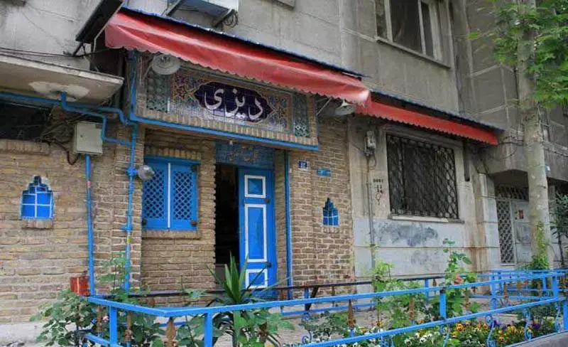 نمای ورودی رستوران دیزی با تابلوی نوشتار دیزی و پنجره‌های آبی، فضایی سنتی و دعوت کننده برای لذت بردن از غذای لذیذ ایرانی.