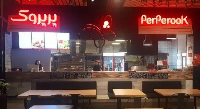 فضای داخلی رستوران پیتزا پرپروک با طراحی مدرن، پیشخوان آماده سازی غذا، پرسنل فعال، تابلوهای نئون و میزهای تمیز برای مشتریان.